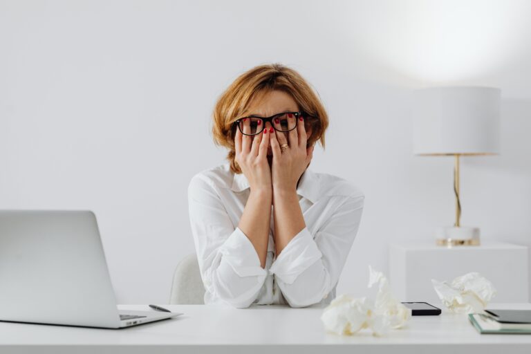 Tolérer la frustration : femme à son bureau, le visage caché dans les mains